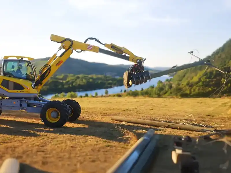 Menzi Muck transportiert Freileitungsmast – Banner zur Kategorie Freileitungsarbeiten