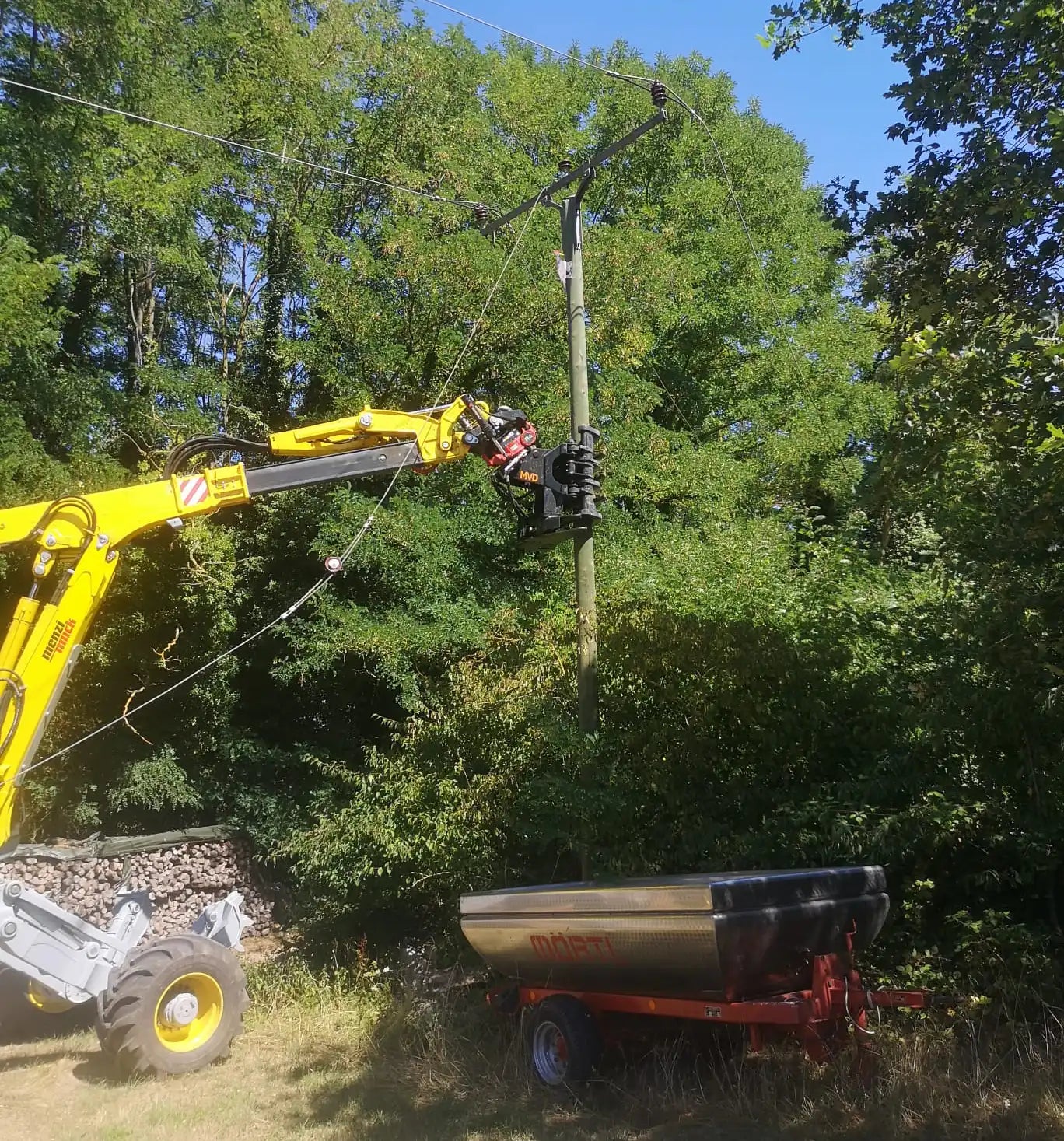 Menzi Muck greift nach Strommast – Referenzbild in der Kategorie Freileitungsarbeiten