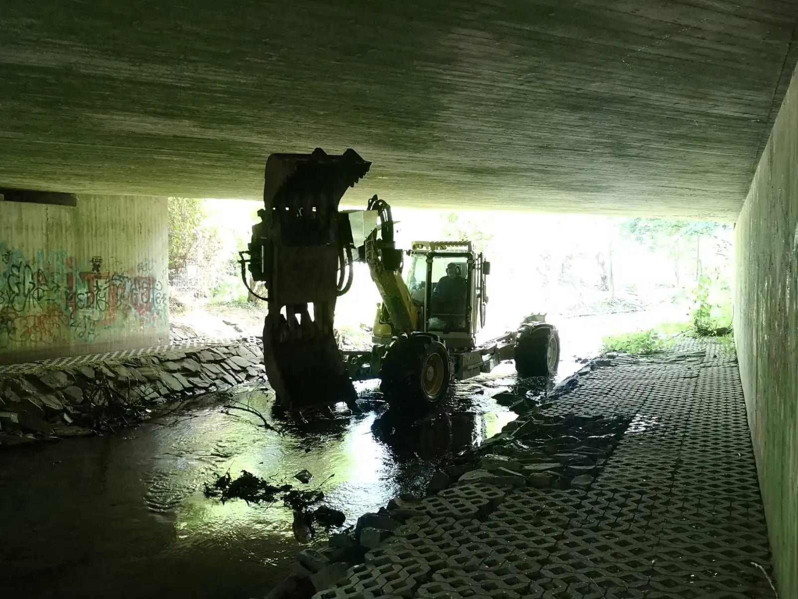Menzi Muck in Bach unterhalb einer Brücke – Referenzbild in der Kategorie Spezialarbeiten